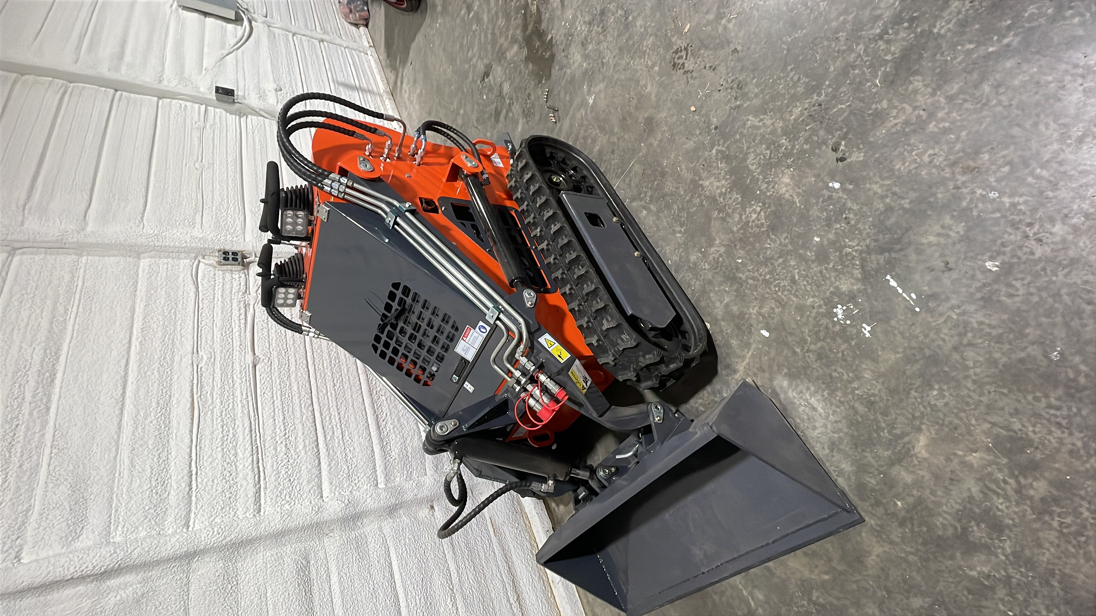 Mini skid steer with bucket and tracks, overhead view