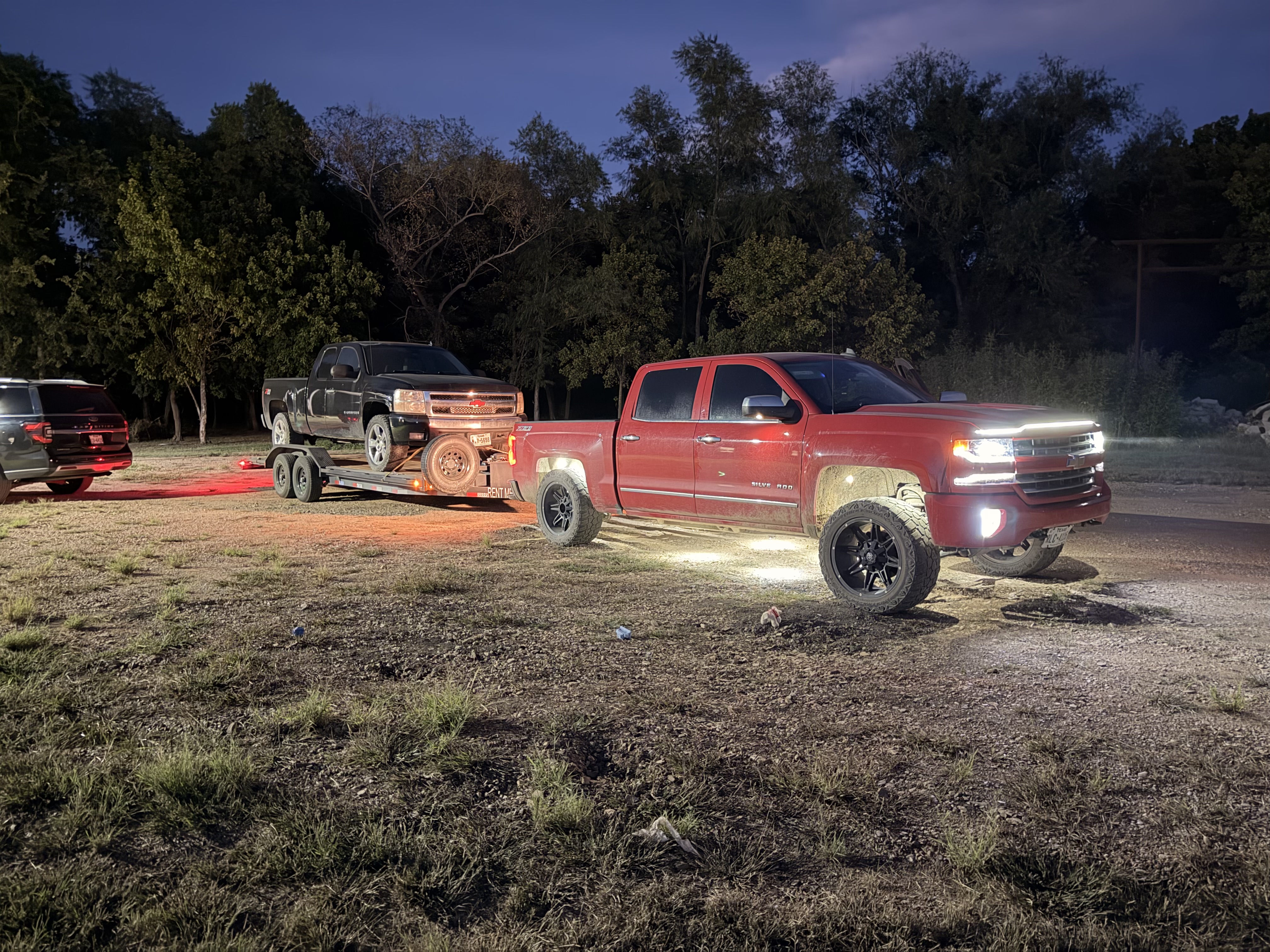 Chevy Silverado towing the car hauler with a truck loaded, dusk